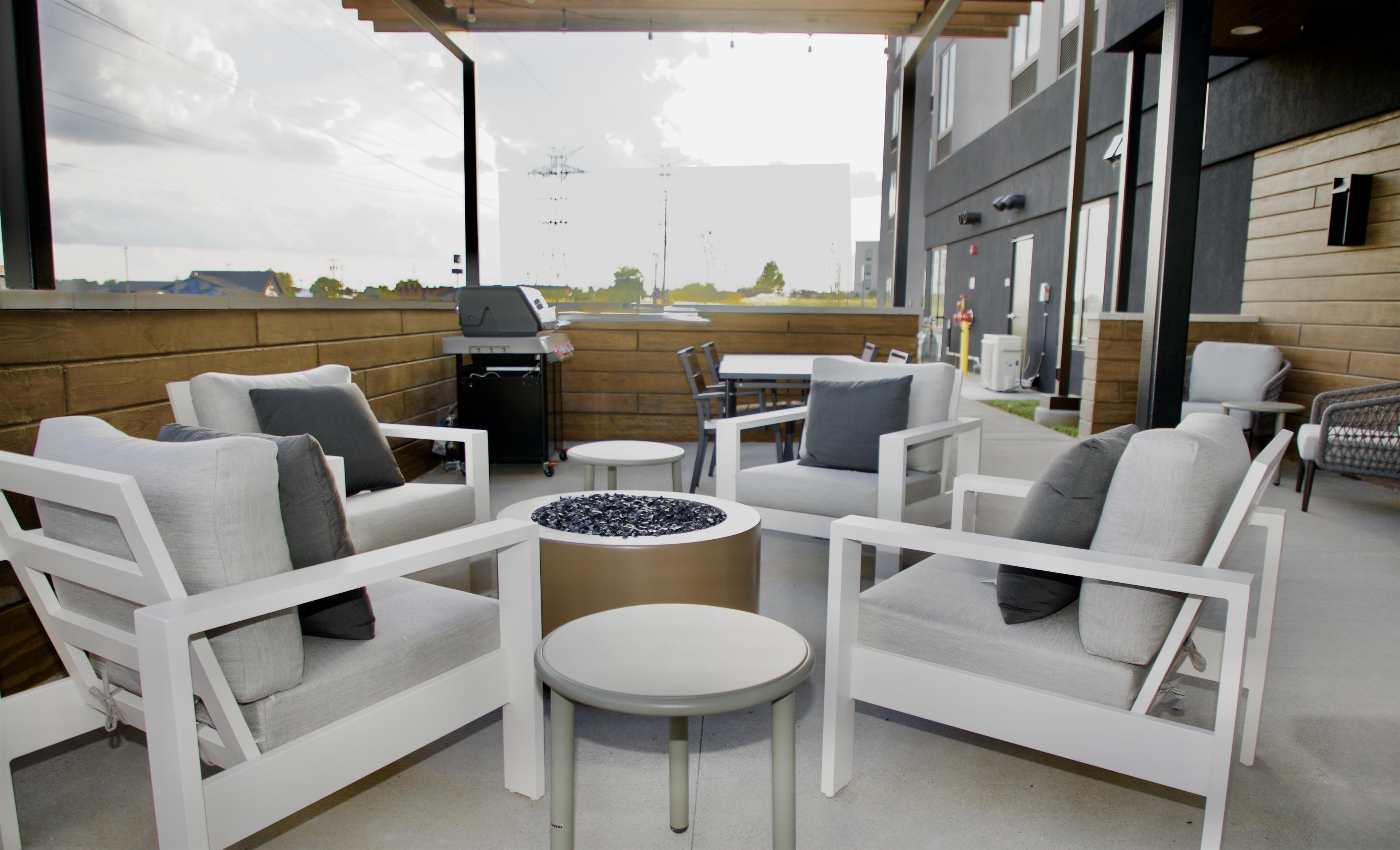 An outdoor seating area with white furniture, a round table, and a grill.