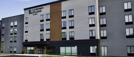 A modern hotel building with a sign for 'LIVSmart Studios by Hilton' and a parking lot with handicapped parking spaces.