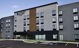 Un moderno edificio de hotel con un cartel que dice 'LIVSmart Studios by Hilton' y un estacionamiento con espacios reservados para personas con discapacidad.