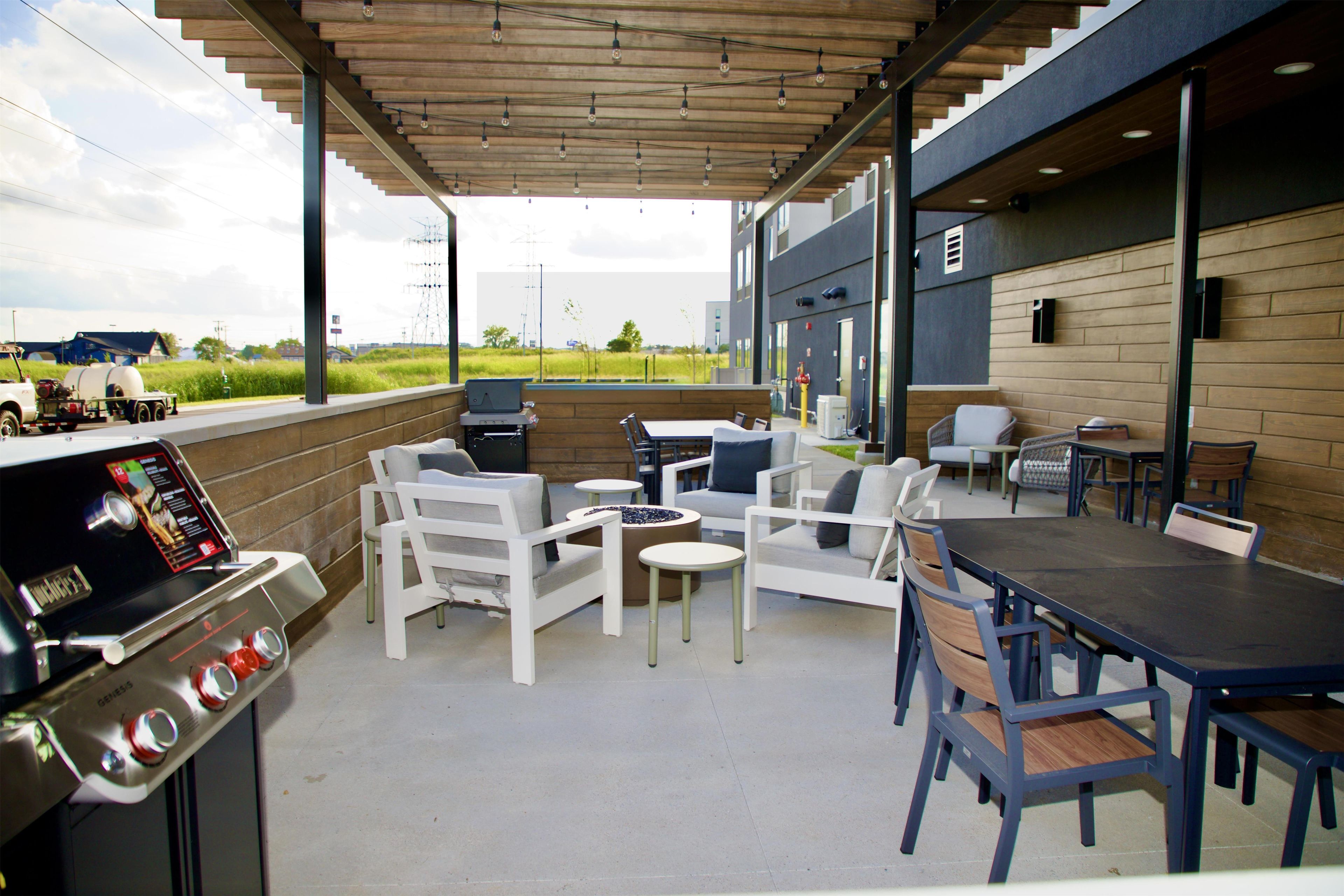 Un espace extérieur aménagé en terrasse, avec un barbecue, des sièges et une vue sur le paysage environnant.