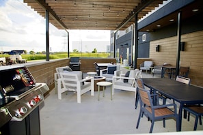 An outdoor patio area with a barbecue grill, seating arrangements, and a view of the surrounding landscape.
