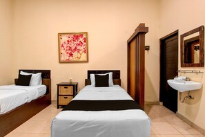 Een hotelkamer met twee bedden, een wastafel aan de muur en een deur naar een andere kamer.