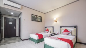 A hotel room with two beds, a painting on the wall, a nightstand, and a door.