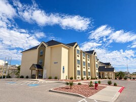 Un hotel de varios pisos con techo plano, número 12211, que cuenta con un estacionamiento con plazas reservadas para discapacitados e hidrante.