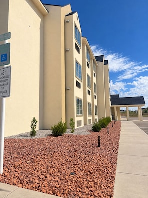 A multi-story building with a parking lot and a clear sky.