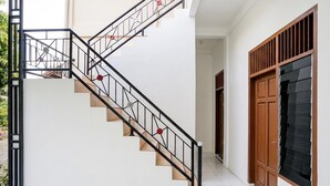 A staircase with metal railings and red accents, a wooden door with a window, and a white wall.