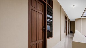 A hallway with a wooden door, a window with blinds, and a tiled floor.