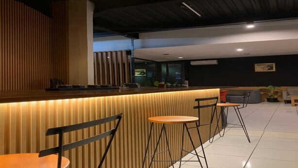 A modern bar area with a wooden counter, black bar stools, and a seating area with a sofa and chairs. - Single Room near Cihampelas Walk (Bandung)