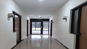 A hallway with a door at the end, a light fixture on the wall, and a tiled floor. - Single Room near Cihampelas Walk (Bandung)