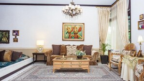 A living room with a sofa, a coffee table, a chandelier, and a painting on the wall.