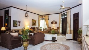 A spacious living room with sofas, a coffee table, a chandelier, and a ceiling fan.