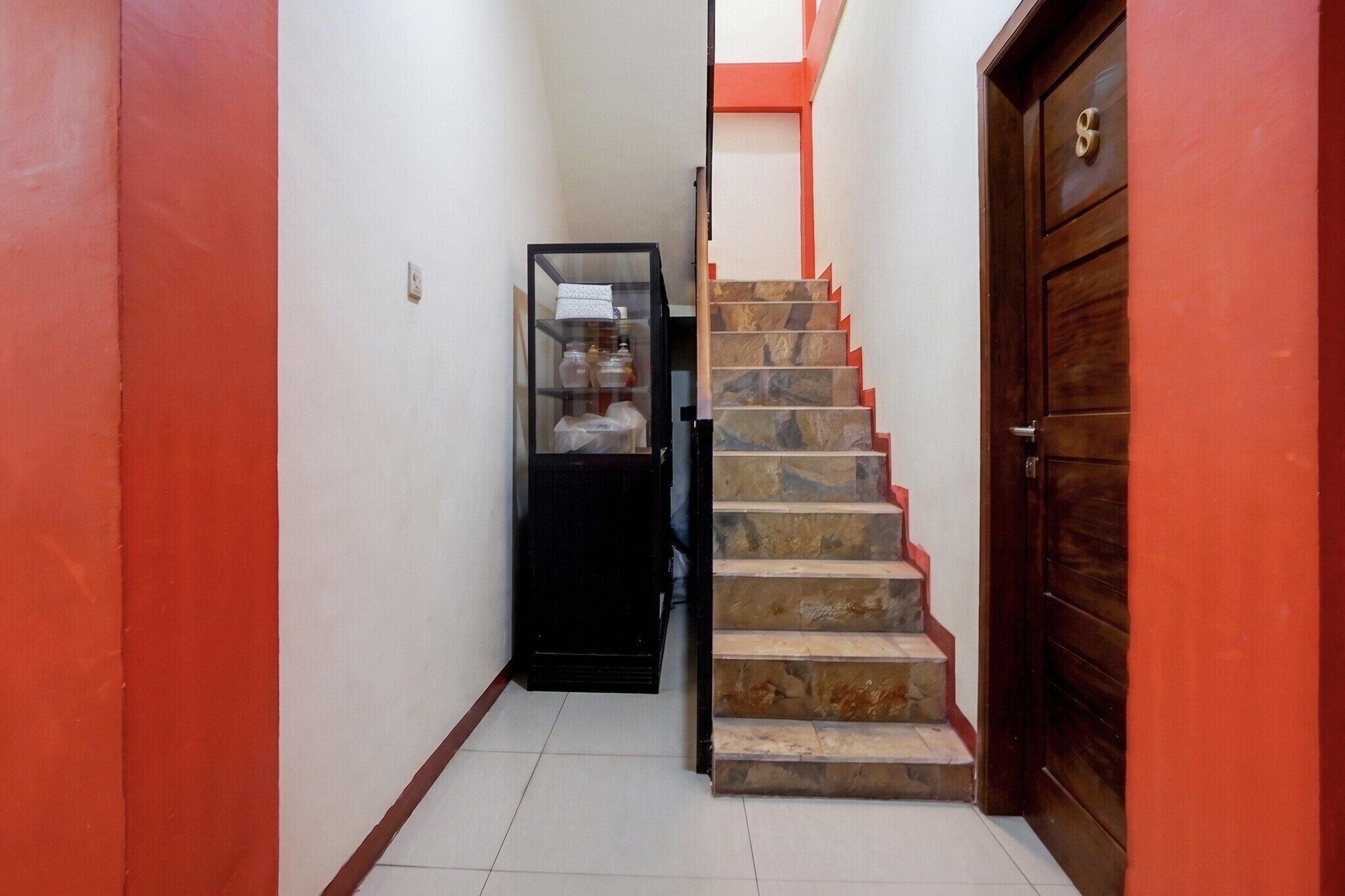 A narrow hallway with a staircase leading to a door.
