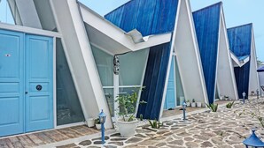 A modern building with blue doors, a stone-paved courtyard, and potted plants.