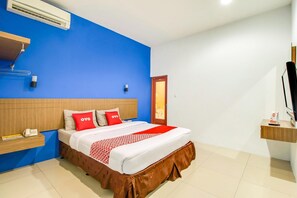 Ein Hotelzimmer mit einem Bett, einem Nachttisch mit Telefon, einer Wand-Klimaanlage und einer Tür.
