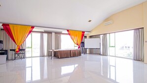 A spacious conference room with a stage, large windows, and curtains.