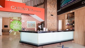 A hotel reception desk with a modern design, a map on the wall, and a sign for the Cassadua Hotel.