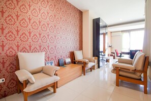Ein modernes Wohnzimmer mit gemustertem Wandpapier, einem Holztisch und zwei Sofas.
