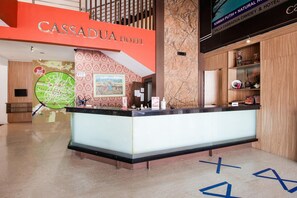 Ein moderner Hotelrezeptionstresen, eine Karte an der Wand und ein Schild für das Cassadua Hotel.
