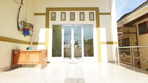 A building entrance with a reception desk, a set of double doors, and a gated area to the right.