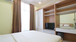 A hotel room with a bed, a TV, a wardrobe, and a mirror.