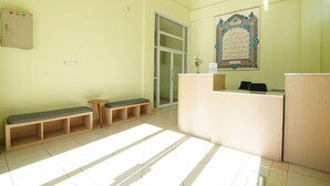 A reception area with a wooden desk, a bench, and a framed calligraphy piece on the wall.