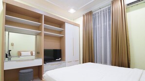 A hotel room with a bed, a TV, a desk with a mirror, and a wardrobe.