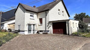 Uma casa de dois andares com garagem, porta da frente e um pequeno alpendre.