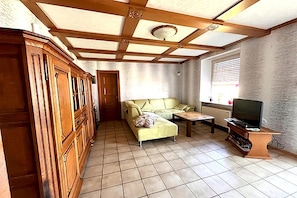A living room with a sofa, television, wooden cabinet, and tiled floor. - Holiday Home in Badem (Badem)