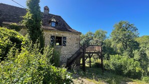 Ein Haus aus Stein mit einer Holztreppe, die zu einem Balkon führt.