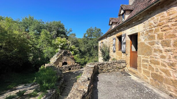 Ein Steinhaus mit rustikalem Aussehen, einem kleinen Bogen und einer Holztür.