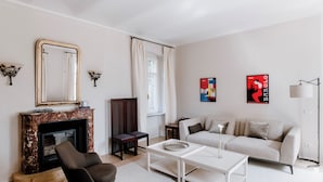 A living room with a fireplace, sofa, coffee table, and artwork on the walls.