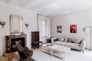 A living room with a fireplace, sofa, coffee table, and artwork on the walls. - Villa Coste di Monforte (Monforte d'Alba)