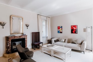 Una sala de estar con chimenea, sofá, mesa de centro y obras de arte en las paredes.