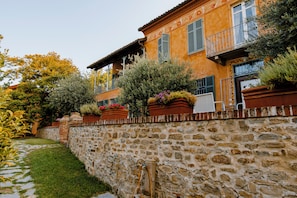 Un muro de piedra con un sendero que lleva a un edificio con varios balcones y jardineras.