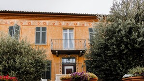 A building with a balcony, a door with a decorative panel, and potted plants.