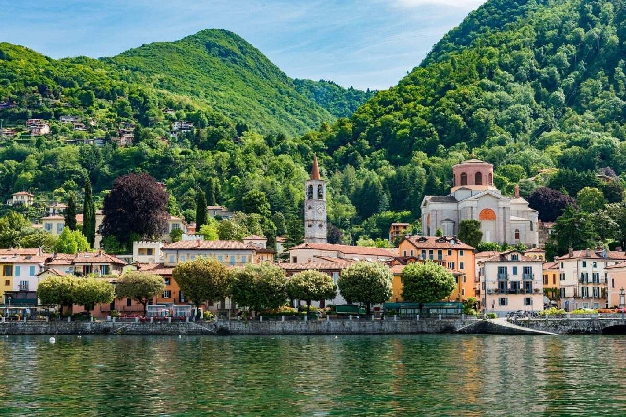 A lakeside town with historic buildings, a church, and a tower.