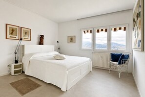 Ein Schlafzimmer mit einem Bett, einem Sessel, einem Heizkörper und einem Fenster mit Blick.
