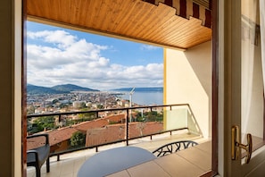 Ein Balkon mit Blick auf eine Stadtlandschaft, ein Tisch und ein Stuhl.