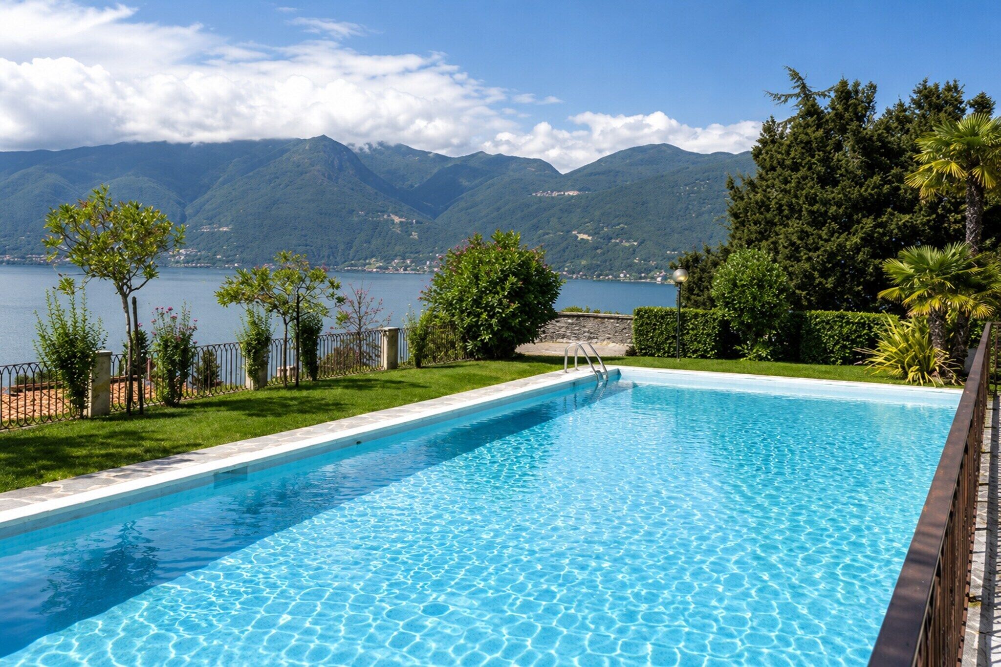 Una piscina con vistas a montañas y un lago.