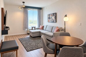 Una sala de estar moderna con un sofá modular, una mesa redonda de madera y una alfombra estampada.