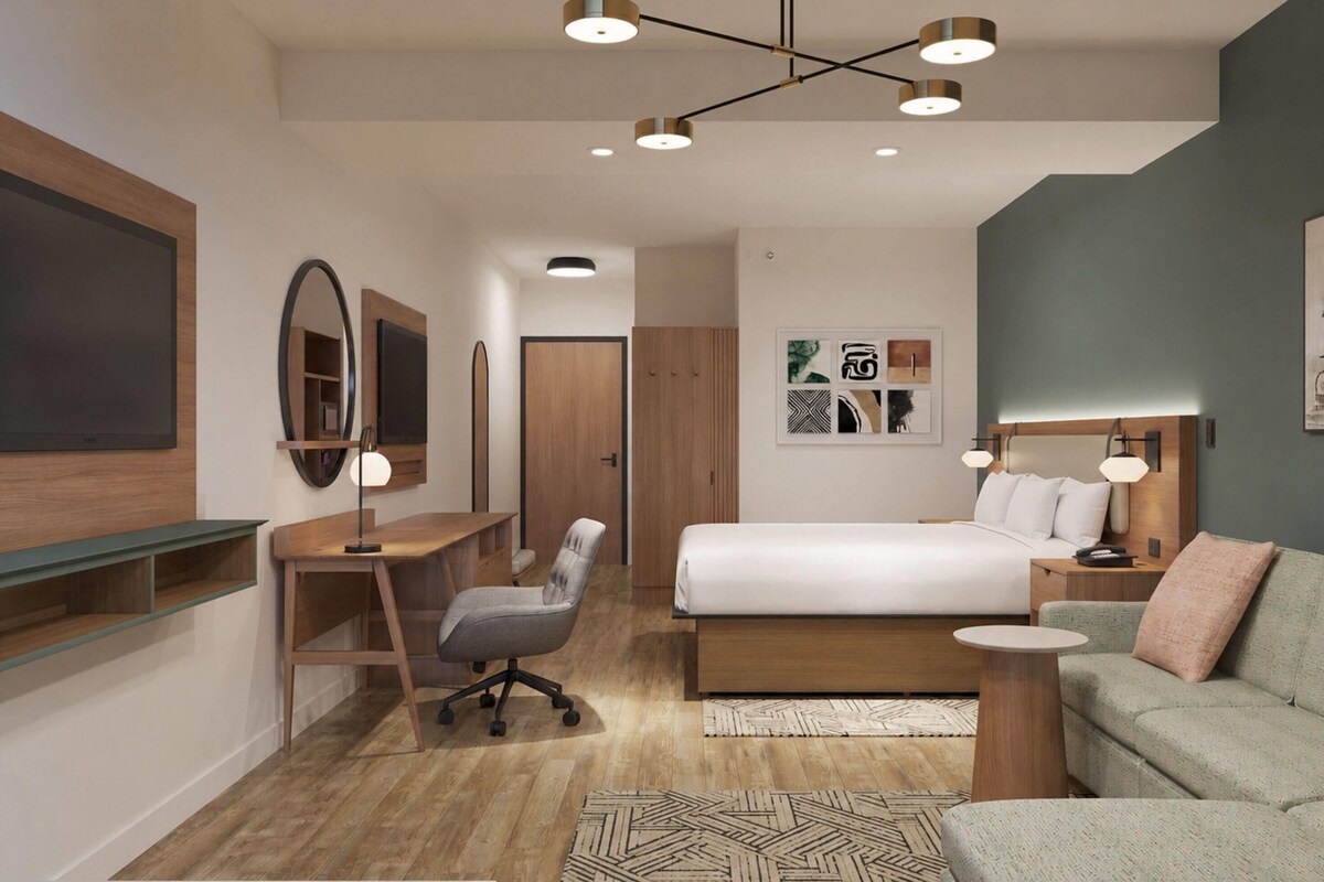 Una camera da letto moderna con un letto, una scrivania, una sedia e un piccolo divano.