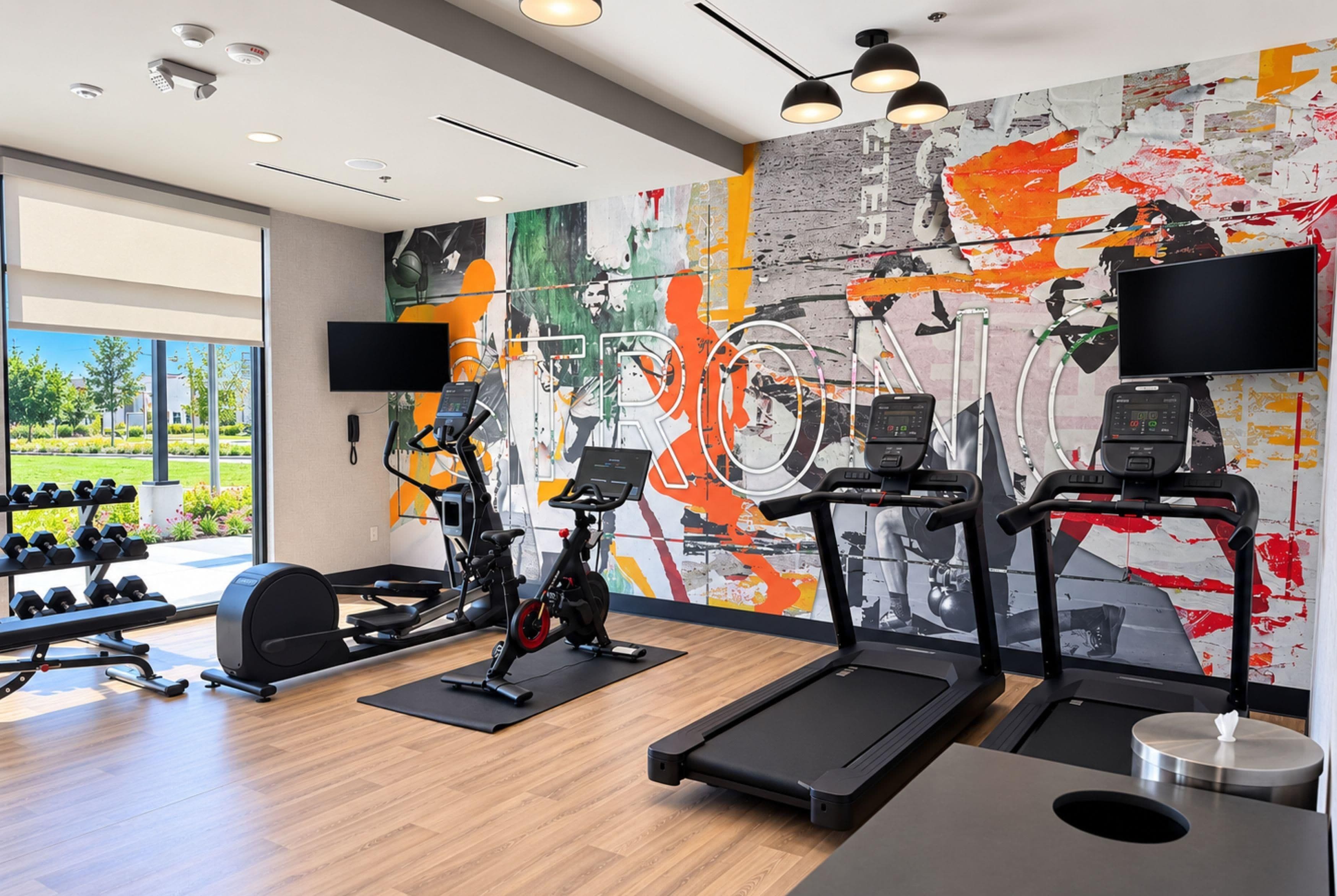 A gym with treadmills, stationary bikes, and dumbbells.