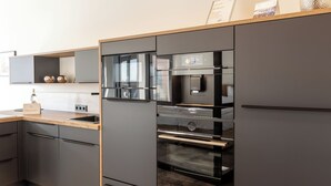 Una cocina moderna con electrodomésticos integrados, encimera de madera y muebles grises.
