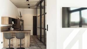 Una cocina moderna con barra, dos taburetes y un ventanal grande.