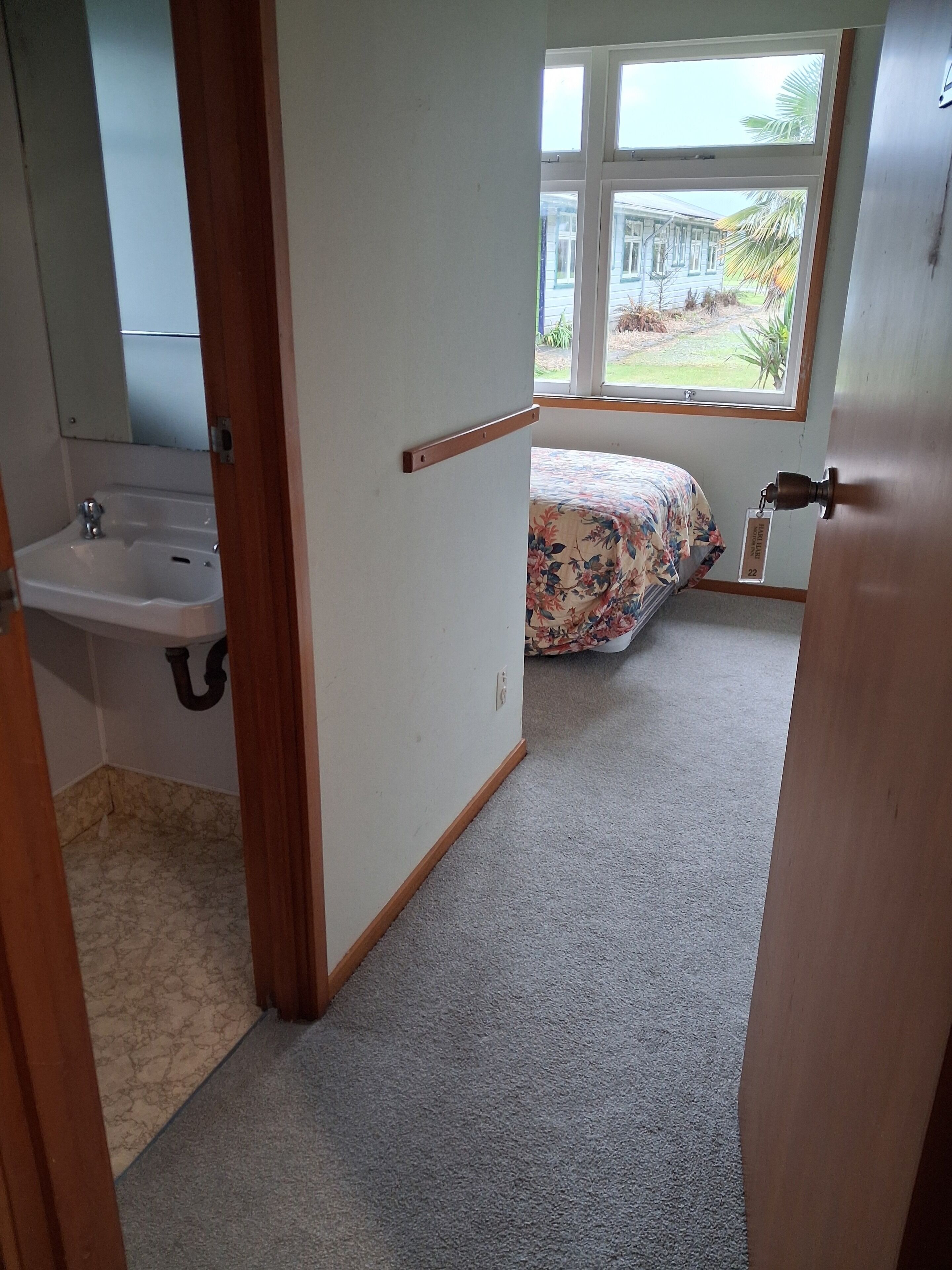 Un dormitorio con cama, ventana y baño con lavamanos.
