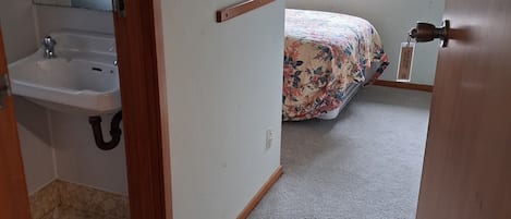 Ein Schlafzimmer mit Bett, Fenster und einem Badezimmer mit Waschbecken.