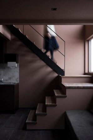 Un intérieur moderne avec un escalier, un coin cuisine et une fenêtre.