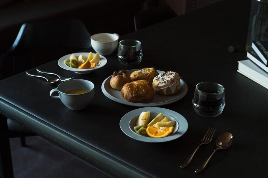 A table with plates of food, a cup of coffee, and a book.