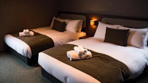 A hotel room with two beds, each with a pillow and a rolled towel. - monel (Nakafurano)