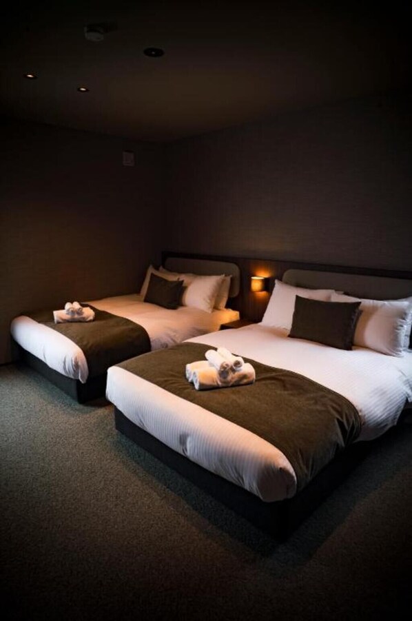Habitaci ón de hotel con dos camas, cada una con almohada y toalla enrollada.